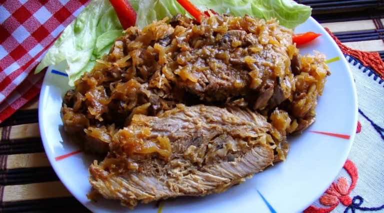 Karkówka pieczona w kapuście kiszonej z pieczarkami.